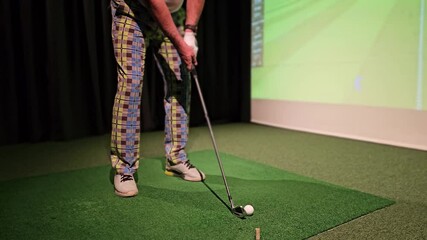 Golf practice session at indoor facility with simulated course on display
