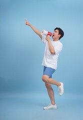 Young man using megaphone to convey message against blue background during daytime