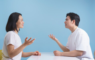 Two friends engaged in a lively conversation at a cheerful indoor setting with a blue background