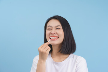 Young woman enjoying dental care while smiling in front of a blue background