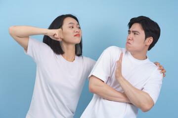 Fototapeta premium Couple playfully engaging in a mock argument against a light blue background in a fun indoor setting