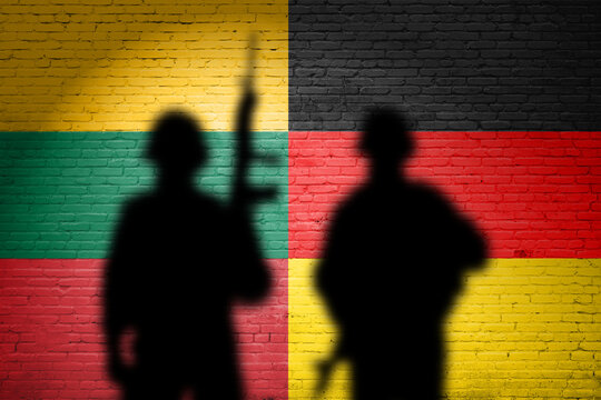 Germany and Lithuania flags painted on a brick wall with soldiers shadows