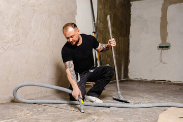 Construction worker vacuuming dust and debris after laying tiles in bathroom