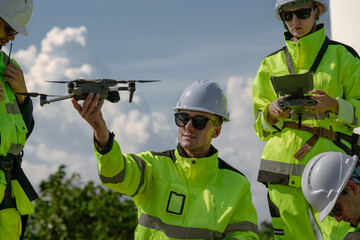 Maintenance engineer team standing at windmills at wind turbine farm. Group of people wear safety...