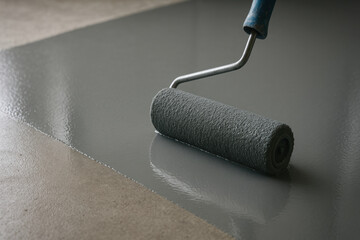 Obraz premium Application of fresh gray epoxy paint on concrete floor with roller