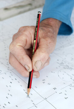 Hand with pencil marking sailing navigation points