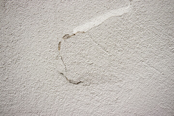Crack in stucco plaster. Light stucco plaster on the wall. Crack in the wall.