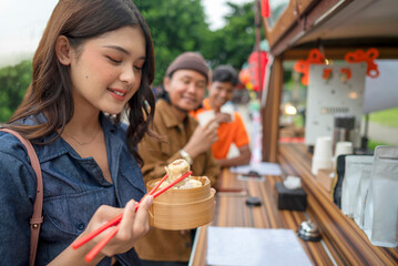 Indonesian southeast asian woman enjoying eating food in front of the shop. A small business on a truck
