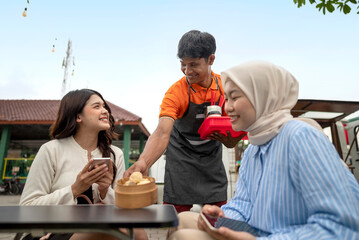 Indonesian southeast asian male barista serving a drink and food to the customer. A small business of a coffee shop or cafe on a truck