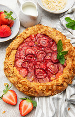 Delicious homemade strawberry galette decorated with almond petals and fresh mint