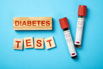 Tube with blood sample for checking blood sugar level with text of diabetes test on wooden cubes....