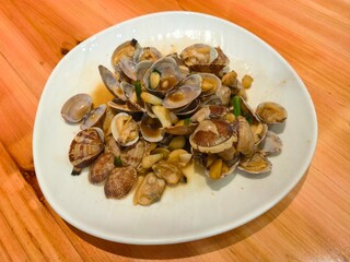 Fototapeta premium Stir-fried clams with garlic sauce served on a white plate