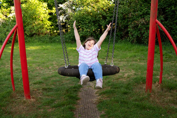 Smiling, happy little girl swinging on a nest swing.