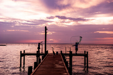 Fototapeta premium Net fishing at sunset in Fairhope , Alabama with dramatic clouds.
