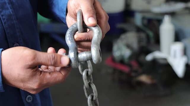 Close up technician hand holding and release the shackle pins attached to the chain.
