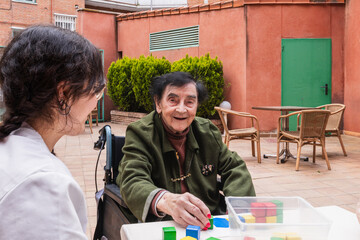 Elderly woman enjoying a therapeutic activity with a caregiver outside at a nursing home, fostering...