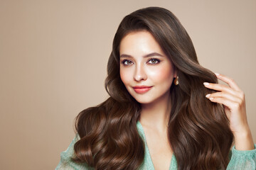 Fototapeta premium Brunette girl with perfect makeup. Smiling beautiful model woman with long curly hairstyle. Care and beauty hair products