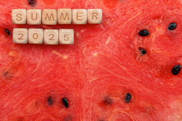 Summer 2025 concept with wooden blocks on juicy watermelon background. Copy space