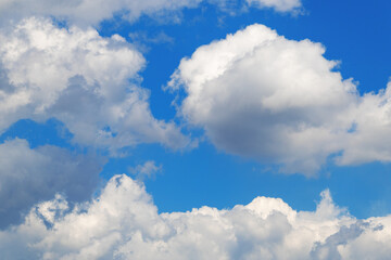 Fototapeta premium Fluffy white clouds against bright blue sky on a clear day