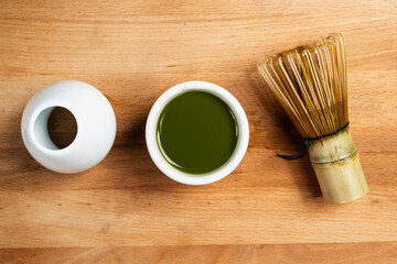 Matcha green tea and a traditional bamboo brush whisk or chasen on a table. Accessories for making...
