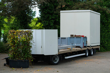 Trailer with storage units parked near greenery in urban setting