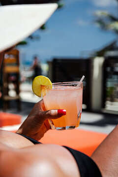 Woman relaxing poolside holding citrus cocktail in Belize sun