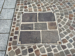 Cobblestone pattern with manhole cover on pavement