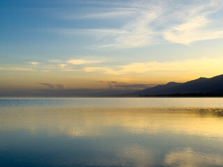 Quiet mountain lake, evening light on the water, Kyrgyzstan. Still water and mountain reflection in...