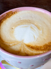 Creamy cappuccino in pink polka dot mug with heart-shaped foam art