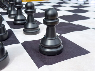 Close-up of large chess pawn on black and white checkered board