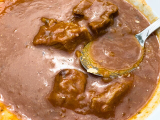 Rich beef goulash with thick sauce and spoon in close-up view