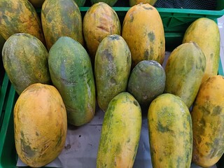 Papaya fruit is neatly arranged as a display in a supermarket or convenience store. 