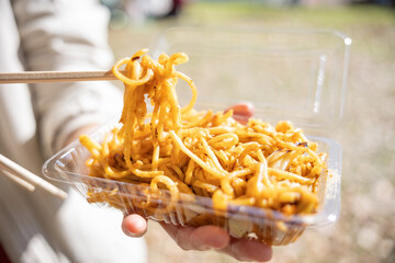 Woman is eating yakisoba (Japanese stir fried noodles). Osaka, Japan