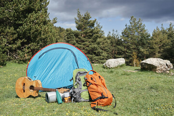 Camping gear and tent in a forest clearing