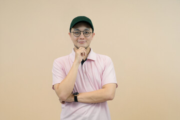 casual young man in cap and glasses posing with confidence on neutral background