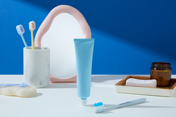 A minimal vanity setup with a blue toothpaste tube, toothbrushes, and pink-edged mirror. Clean...