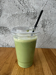 Refreshing iced matcha latte in clear cup on wooden table