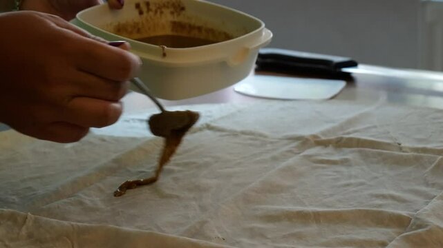 Poppy and tahini mixture is spread on the yufka. Homemade borek making.