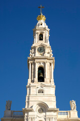 The bell tower of the Sanctuary of Fatima rises towards a clear blue sky