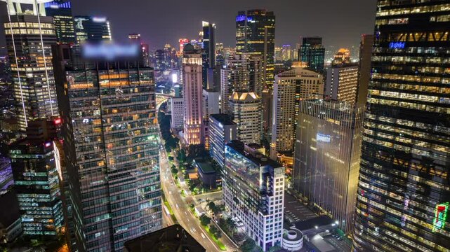Aerial timelapse of Jakarta business district at night with busy traffic, illuminated skyscrapers, and city skyline. Ideal for city, business, travel, and infrastructure themes.