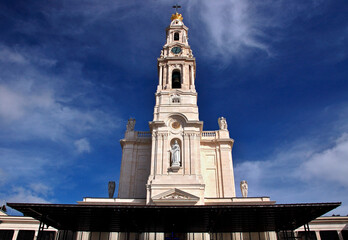 The bell tower of the Sanctuary of Fatima rises towards a clear blue sky