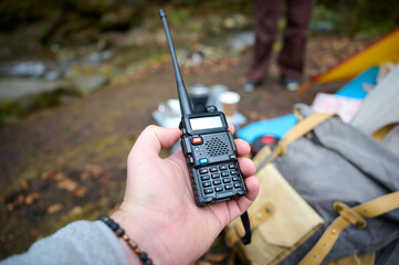 Man holding radio station near camping tent. Walkie talkie in the mountains. Concept of wireless communications. Off grid communication methods.