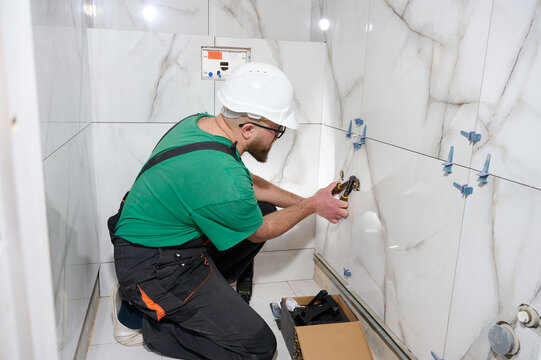 Plumber installing a handheld bidet sprayer. Plumbing for wall mixer. Wall mounted tap or shower mixer. Handheld bidet spray in toilet. Hygienic shower with mixer. Best drain snaking services.