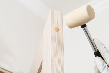 Installation of door plugs by a master using a rubber hammer, close-up