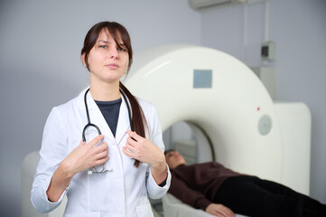 Female radiologist with a patient in a scanning room. Adorable doctor in CT scan room. Radiologist with a female patient in the room of computed tomography. Modern clinic. Radiology department.