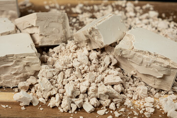Compressed fresh yeast cubes close-up on a wooden background.