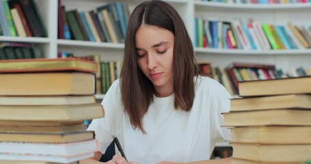 Student collecting information from different books, Caucasian girl in white t-shirt gathering data for the paper. Self education concept.