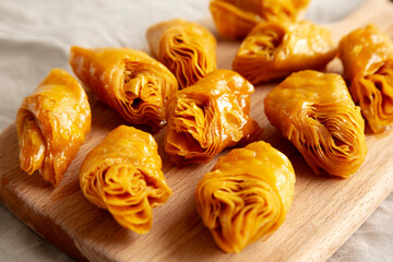 Sweet Homemade Turkish Baklava with Honey on a Wooden Board, side view.