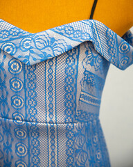 Cocktail dress coated with blue lace, off-shoulder bandeau bodice, close-up details. Silhouette gown on dummy. Neckline design. 