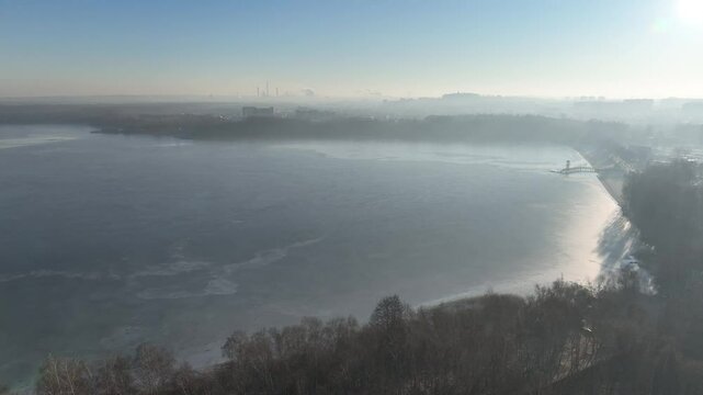 Steelworks in the fog. Frozen lake in the morning fog on a sunny day. Pogoria lake in winter, Dabrowa Gornicza, Poland. Ice shrouded lake in fog aerial shot from a drone.